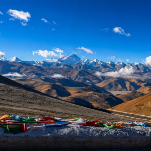 Panoramic view of the Himalayan mountain range from the Tibetan plateau featuring the North Face of Mount Everest under a clear blue sky.